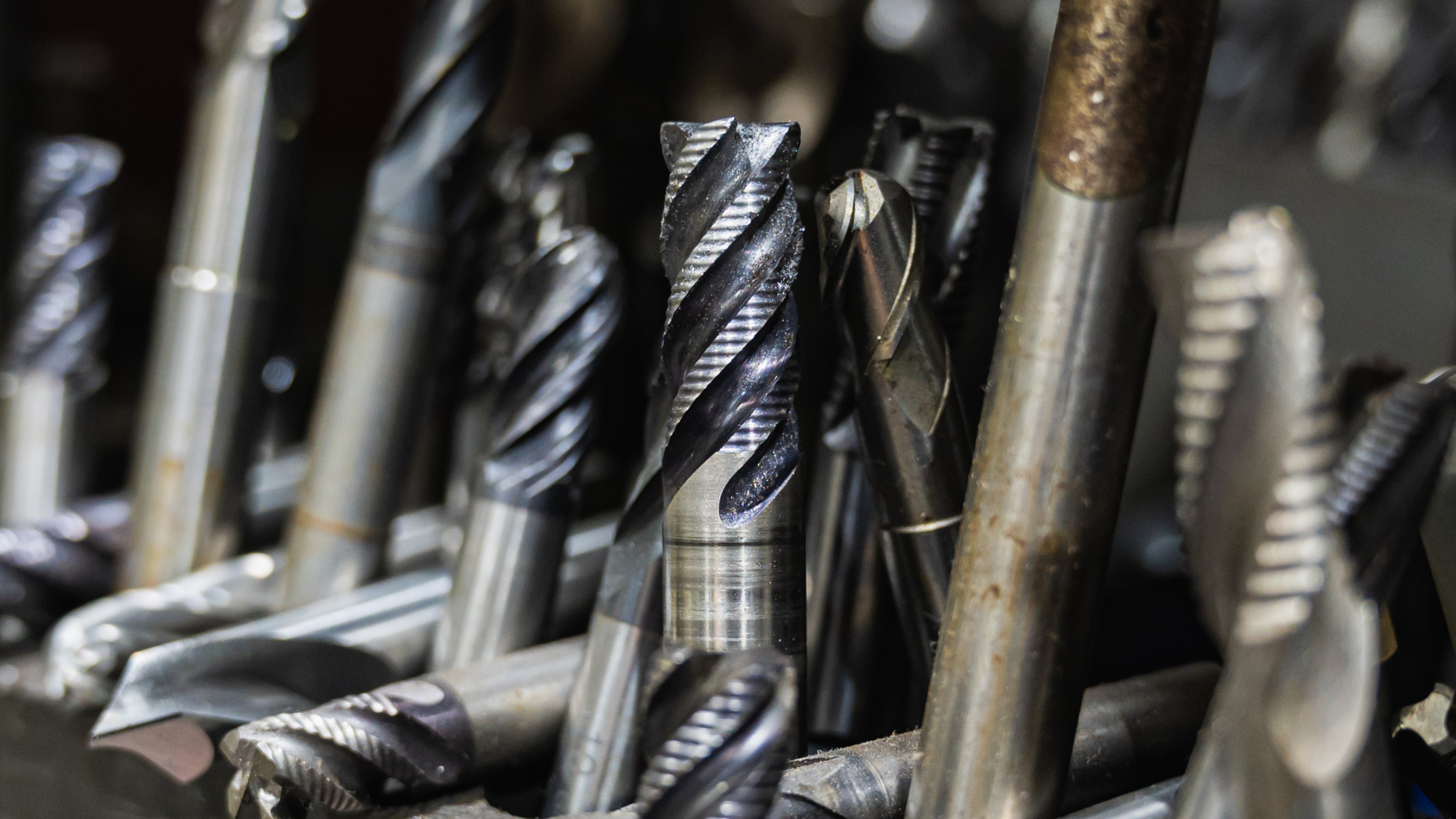 Close-up of various metal drill bits and end mills, showcasing their different shapes and cutting edges.